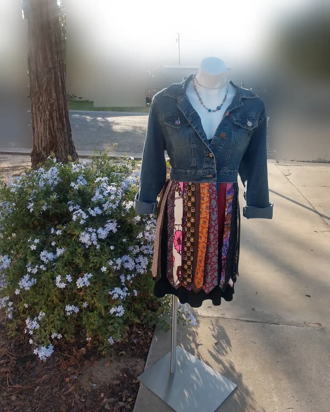 Dress form outdoors wearing a cropped denim jacket and a multicolor tie-neck skirt.